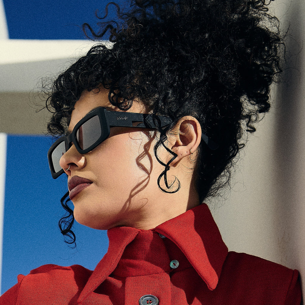 Side profile of a woman wearing black rectangular sunglasses with black polarized lenses.