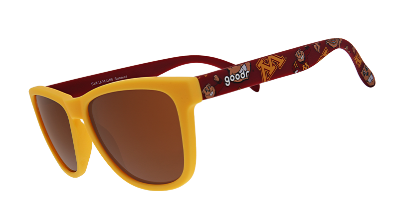 A pair of "goodr" sunglasses with yellow frames and brown-tinted lenses. The arms of the sunglasses feature a maroon background with gold University of Minnesota "M" logos and mascots, creating a collegiate-themed design.