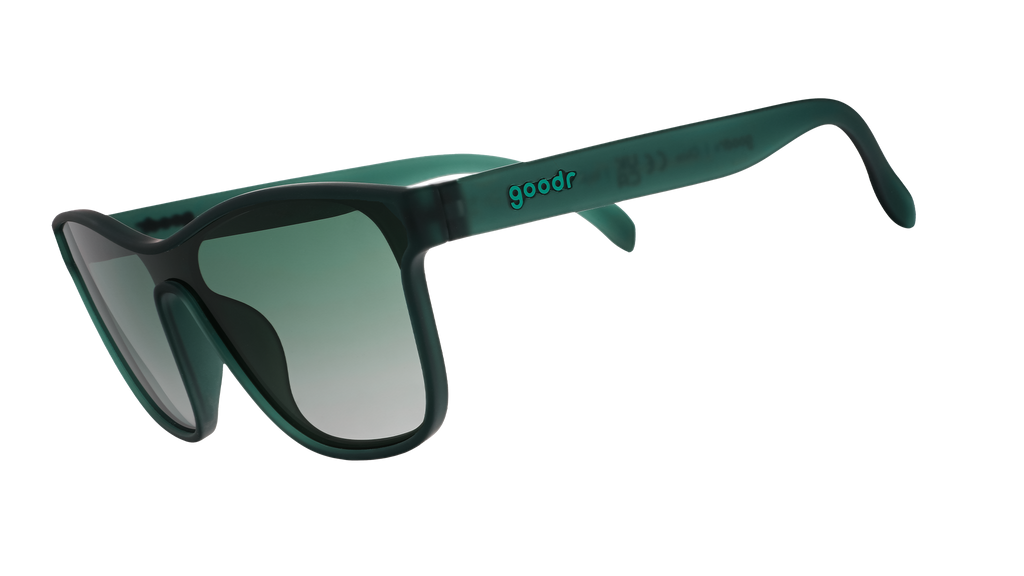 Three-quarter angle view of translucent teal one-lens sunglasses with green gradient lenses.