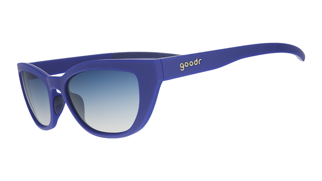 Three-quarter angle view of navy blue cat eye shades with blue gradient lenses tilted down on a white background.