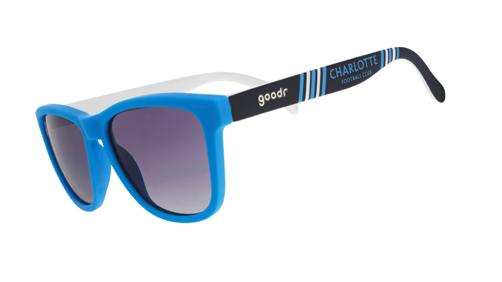Three-quarter angle view of MLS Charlotte FC shades tilted down. Blue+black frames. Black gradient lenses.