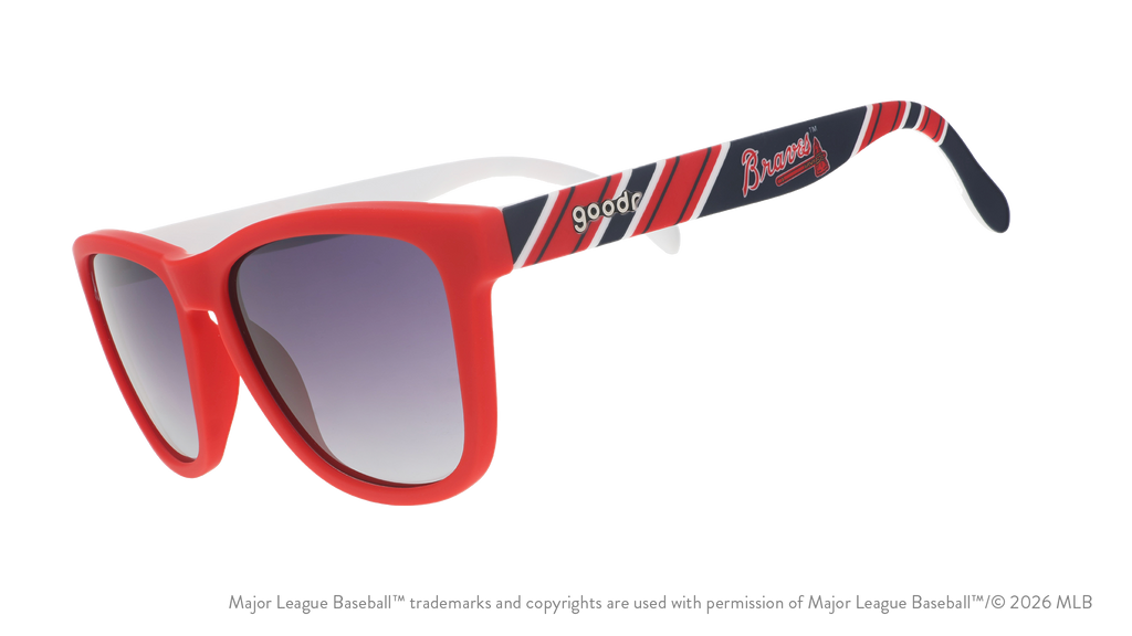 Three-quarter angle view of red, white, and navy Braves sunglasses featuring the script and tomahawk logo on the arm.