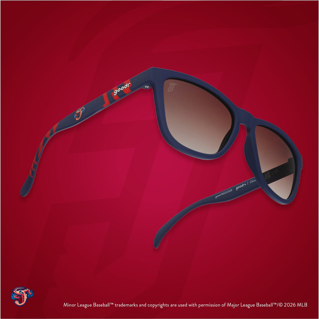 Three-quarter angle view of shades tilted up. Blue + red frames w/ Jumbo Shrimp logo on temples. Brown gradient lenses.