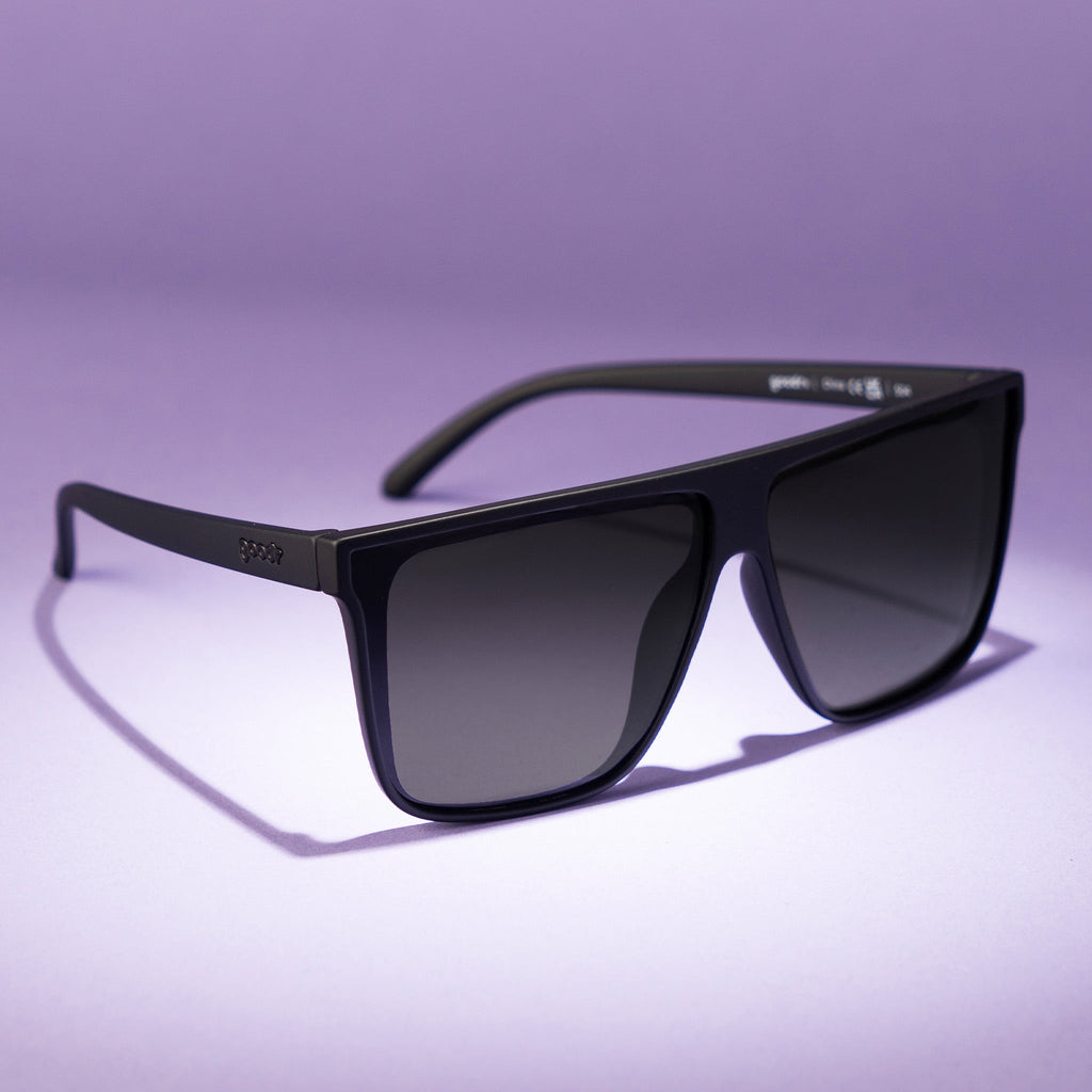 Three-quarter view of a pair of fashionable oversized black flat-top glasses with black non-reflective lenses.