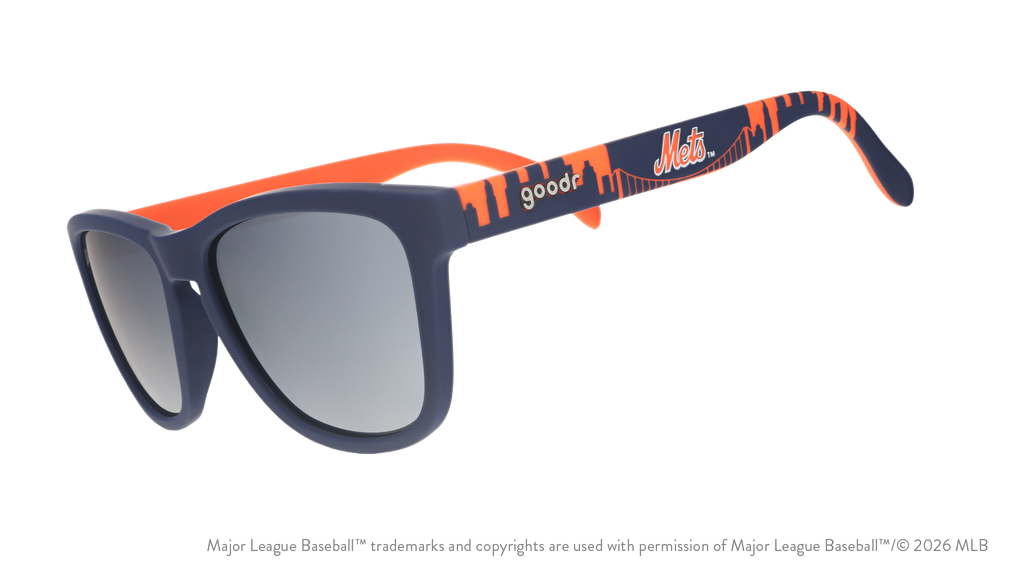 Three-quarter angle view of blue and orange Mets sunglasses featuring the script logo and a New York City skyline on the arm.