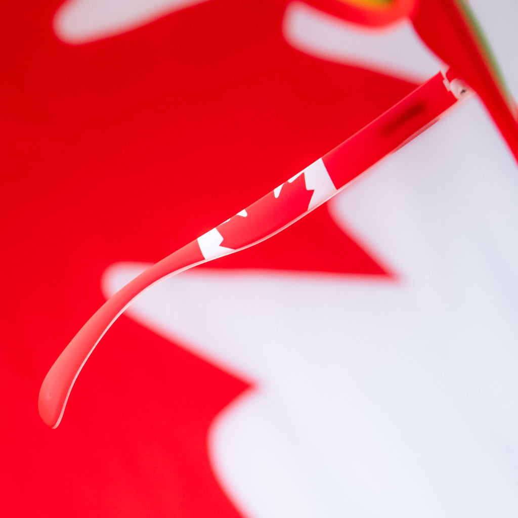 Angled view of red shades w/ a Canadian flag pattern+burnt orange reflective lenses on a stylized background.