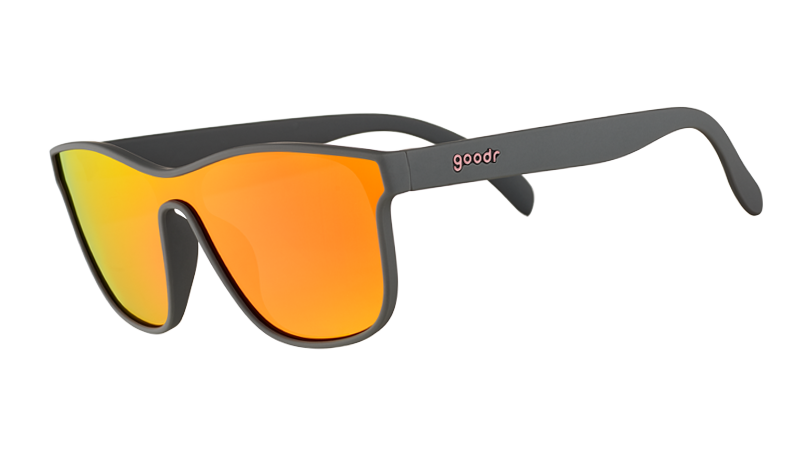 A pair of single lens goodr sunglasses with gray frames and orange/yellow reflective lenses on a white background.