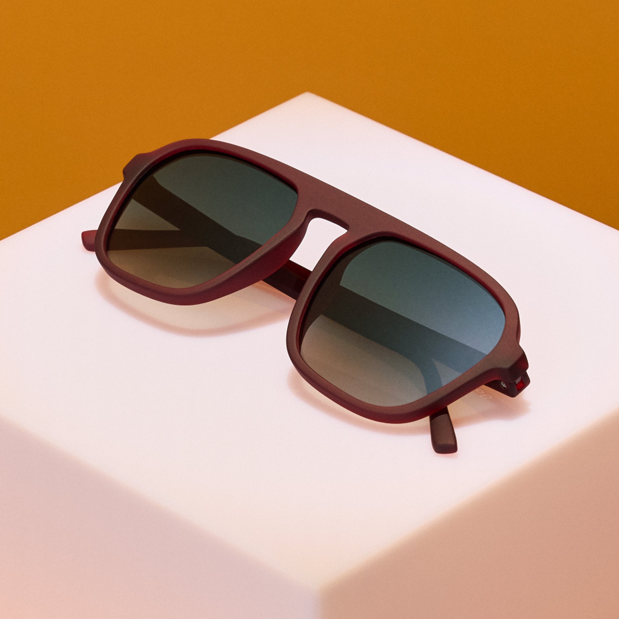 Sunglasses with dark lenses on a white surface with a brown background