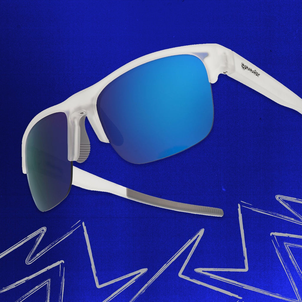 Three-quarter angle back view of clear shades w/ half-rim frames+blue reflective lenses tilted up on a blue background.