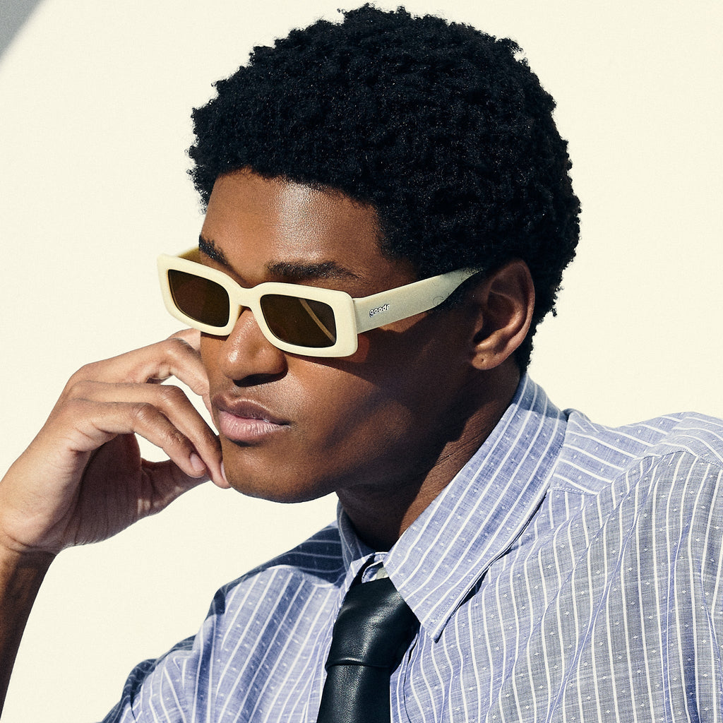 A man poses, wearing yellow rectangular sunglasses with brown-tinted polarized lenses.