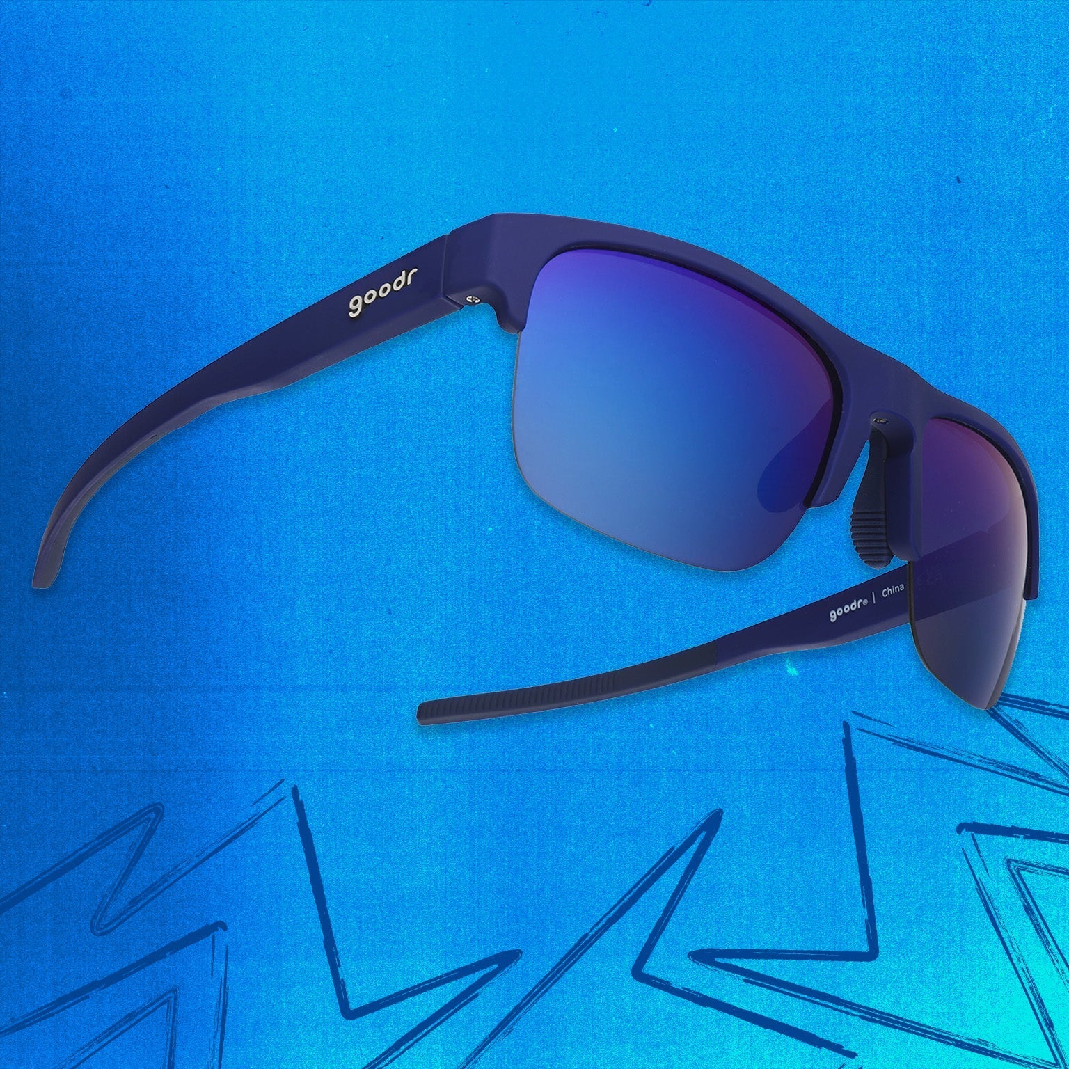 Three-quarter angle view of navy blue sunnies with half-rim frames+blue gradient lenses tilted up on a blue background.
