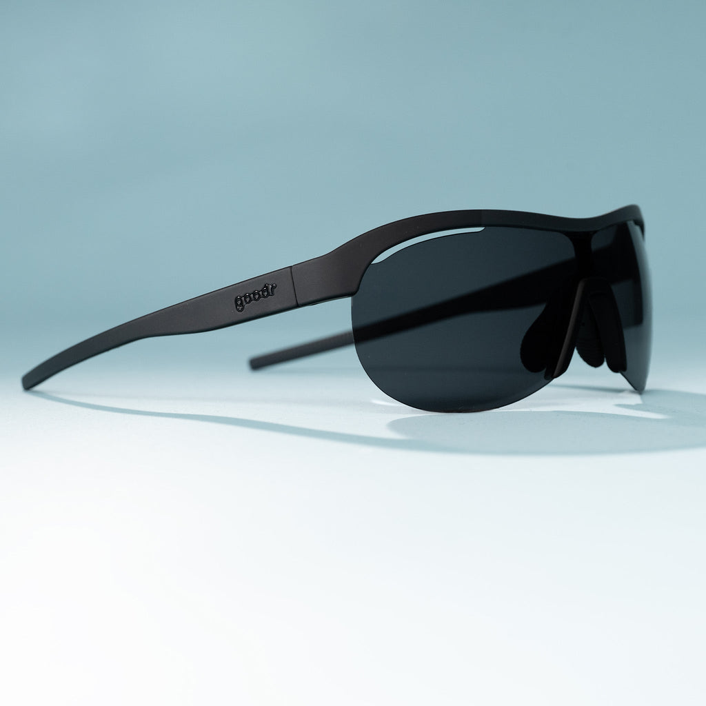 Right three-quarter view of black wraparound shield sunglasses with black polarized lenses on a tabletop.