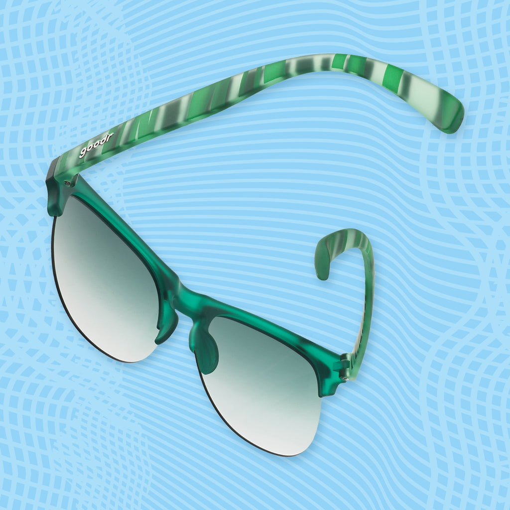 Angled view of green mirrored sunglasses with striped arms against a blue patterned background.