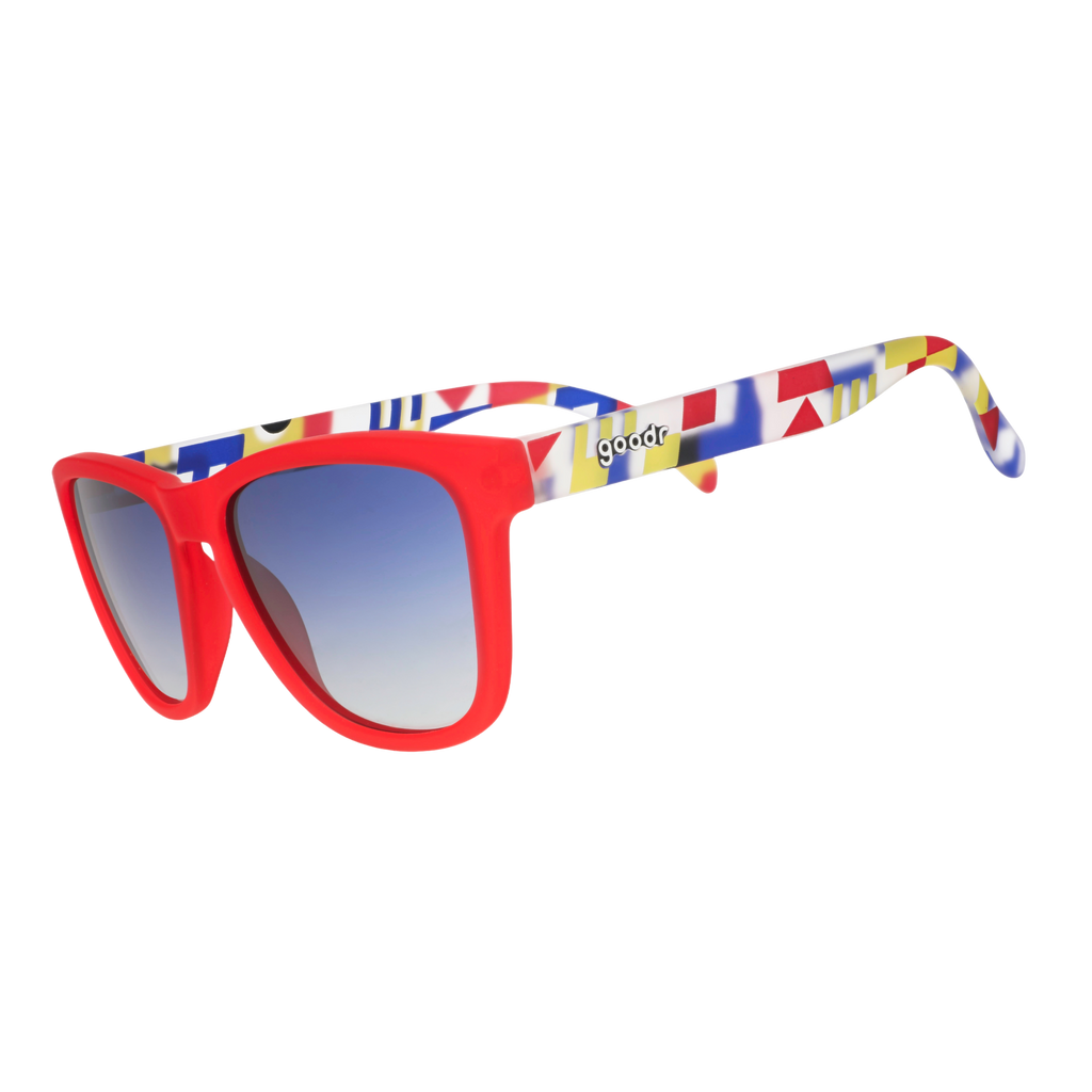 Three-quarter angle view of red sunglasses with multi-colored arms depicting maritime signal flags, and blue gradient lenses.