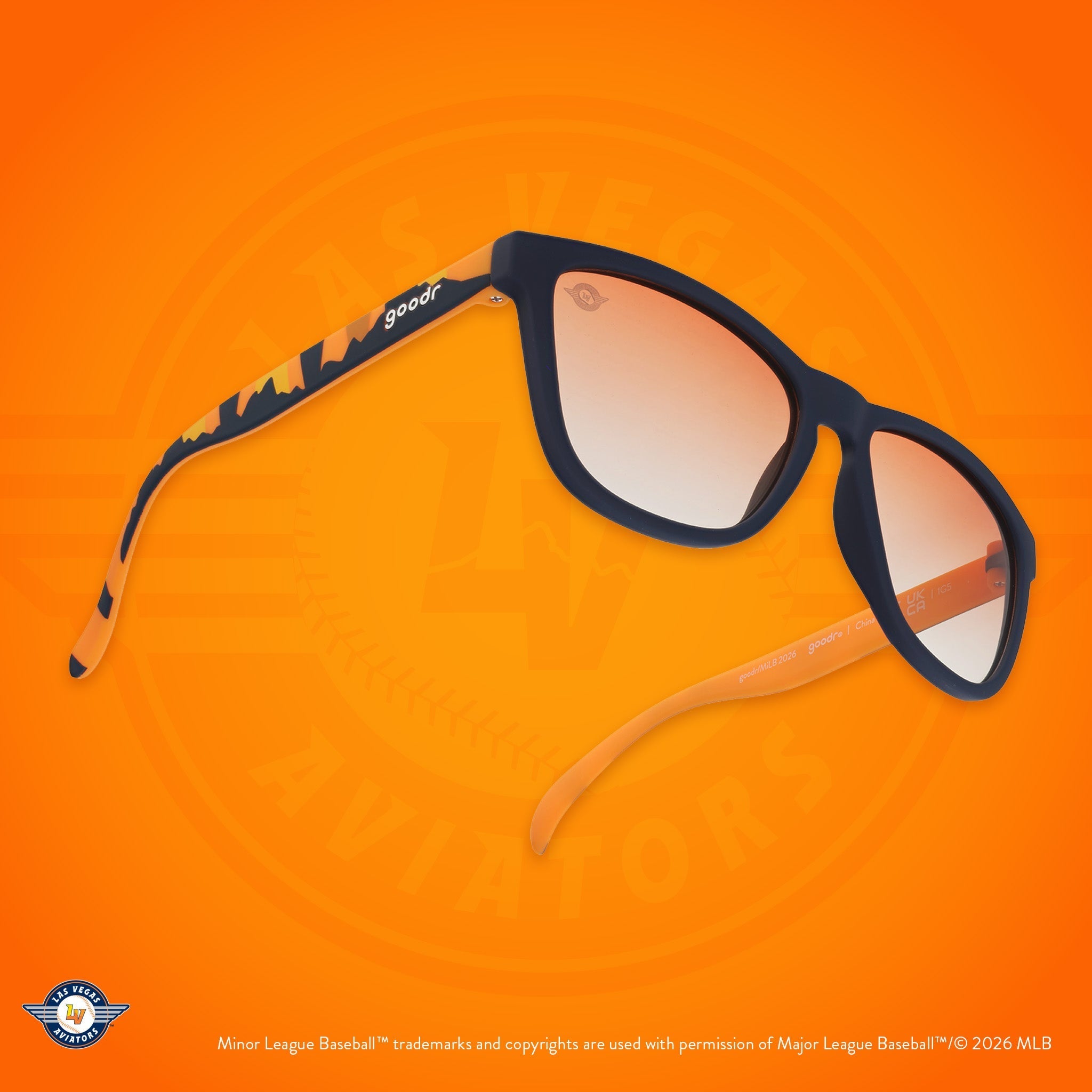 Angled view of shades. Blue frames w/ an orange+yellow landscape + Aviators logo etching on orange gold gradient lenses.