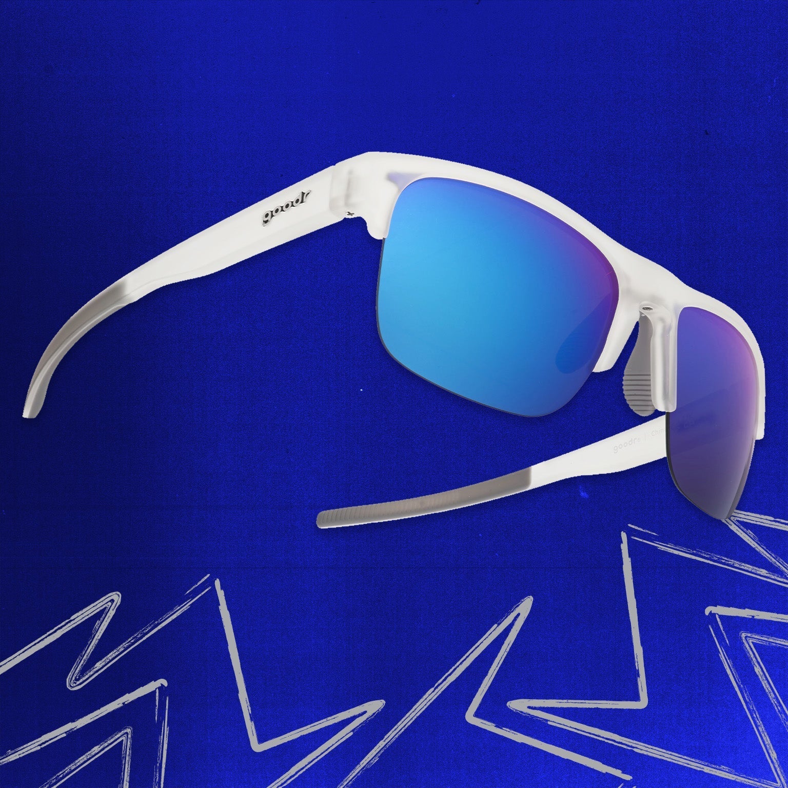 Three-quarter angle view of clear sunnies with half-rim frames+blue reflective lenses tilted up on a blue background.