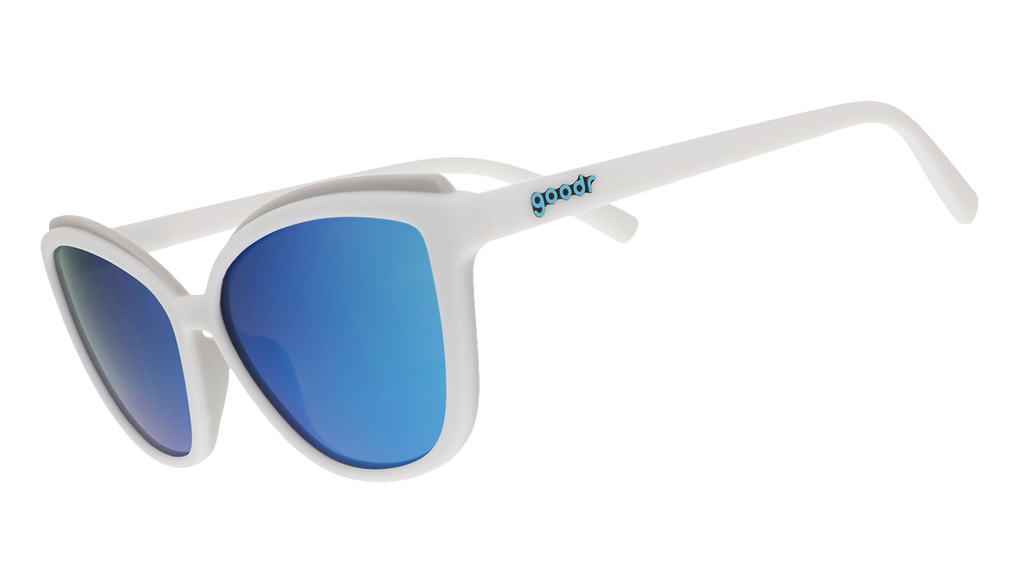 White cat-eye sunglasses with light blue mirrored lenses on a blue patterned background.
