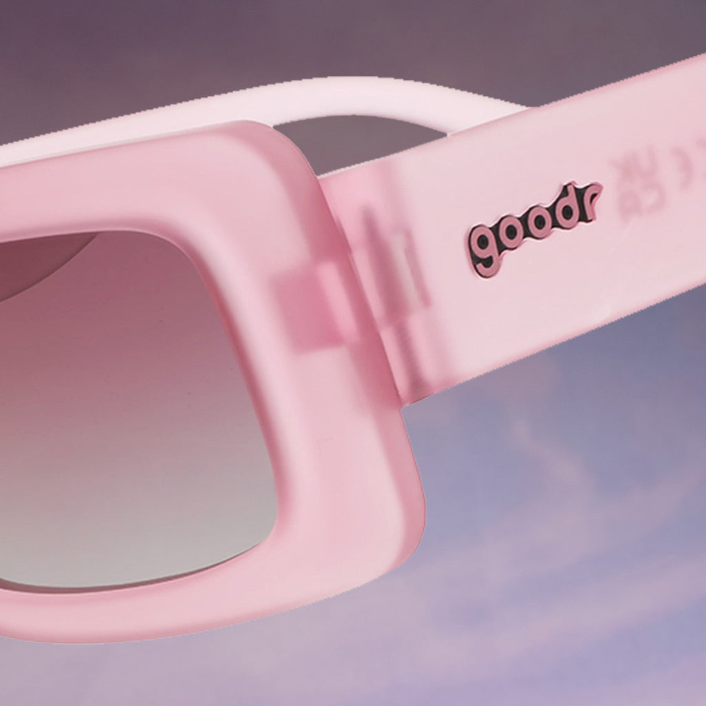 A close-up shot shows the goodr logo on a pair of translucent pink Luxe Gs floating against a purplish cloud-like backdrop.