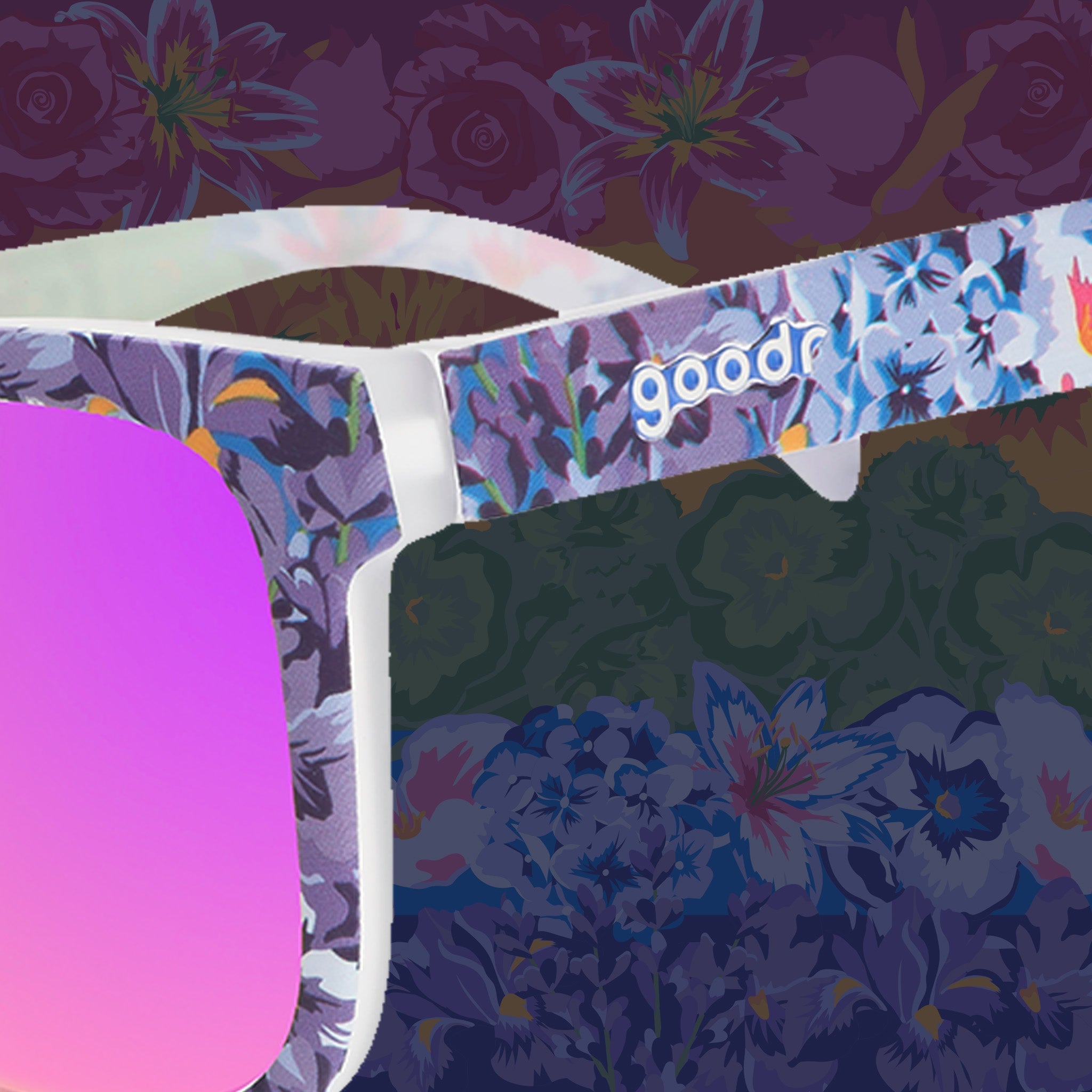 Close-up of colorful floral print goodr sunglasses with purple reflective lenses against a floral background.