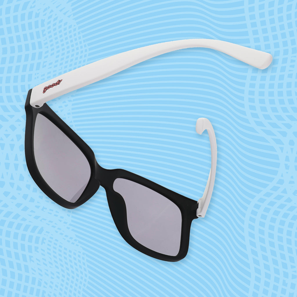 Angled lifestyle view of black square sunglasses with black lenses and white arms.