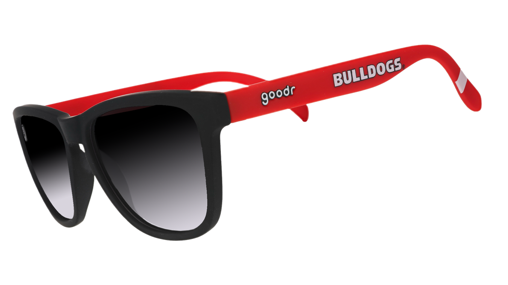 A pair of sunglasses with black frames and lenses, and red temples that have the word "Bulldogs" written in white along the side.