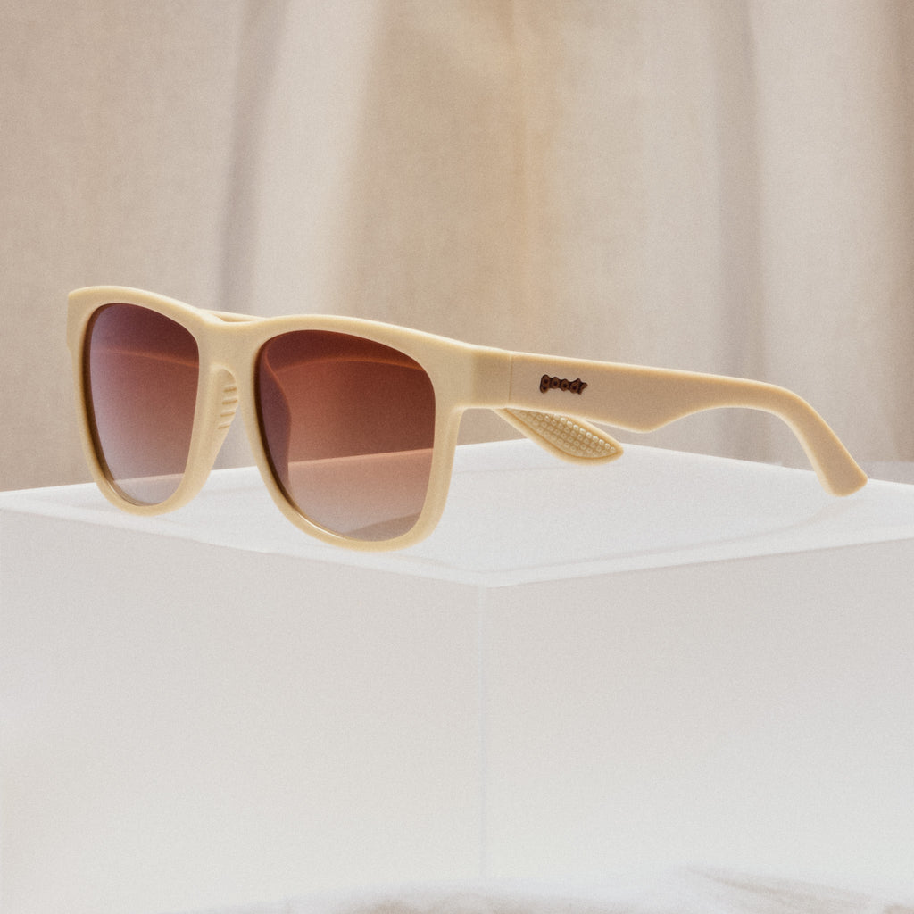A pair of square sunglasses with tan frames and burnt orange lenses.