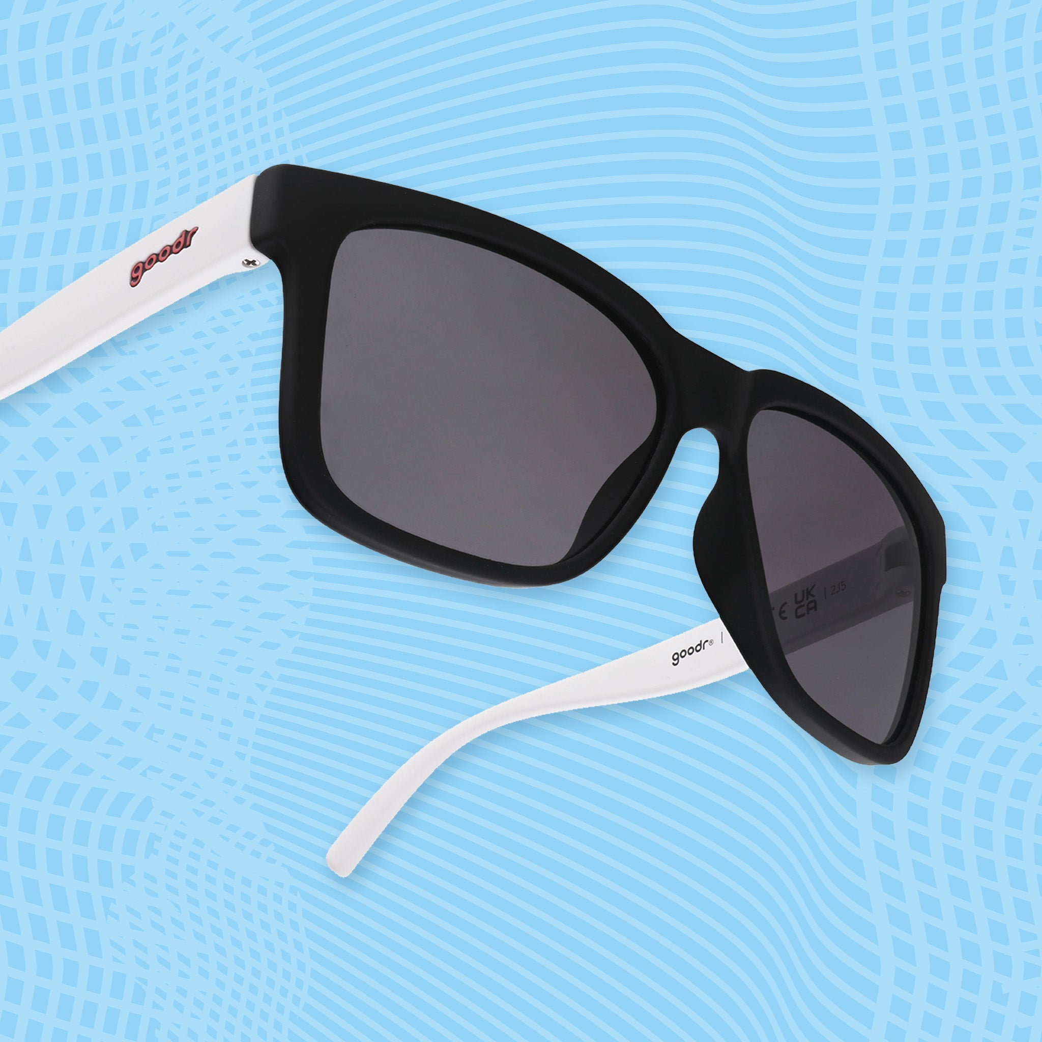 Black square sunglasses with black lenses and white arms on a blue patterned background.