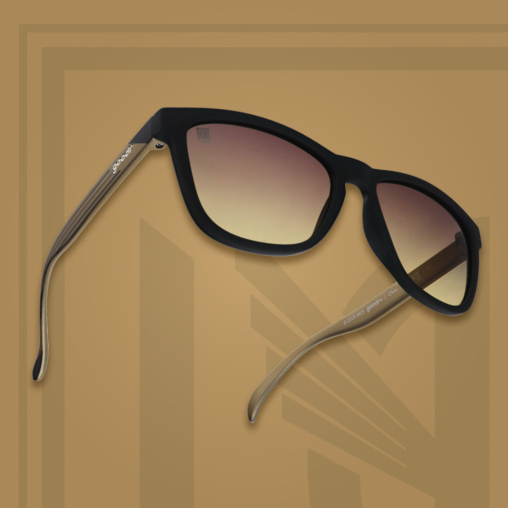 Three-quarter angle view of LAFC shades tilted up. Black and gold frames. Gray-yellow lenses. Gray-yellow background.