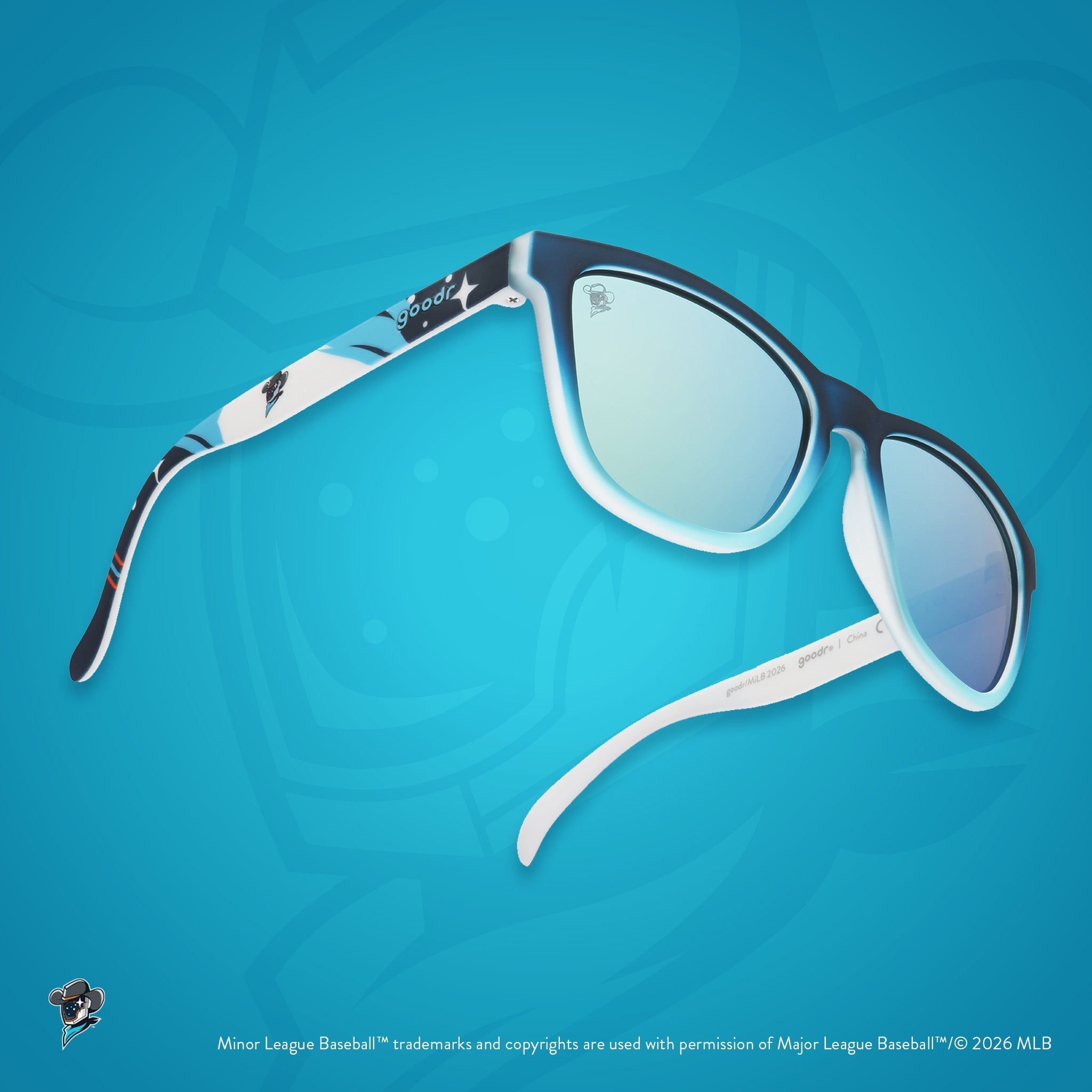 Three-quarter angle view of sunglasses. Blue frames w/ stars, Space Cowboys logo on temples + blue reflective lenses.